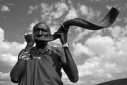A Masai warrior blows a Kudu horn